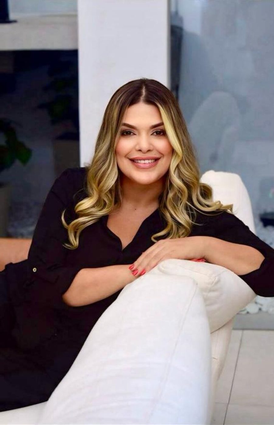 Retrato da Dra. Stephanie Alves, sorrindo, sentada em sofá claro